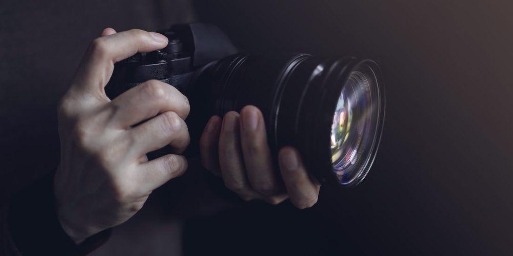 Young Photographer Woman using Camera to Taking Photo. Dark Tone. Selective Focus on Hand